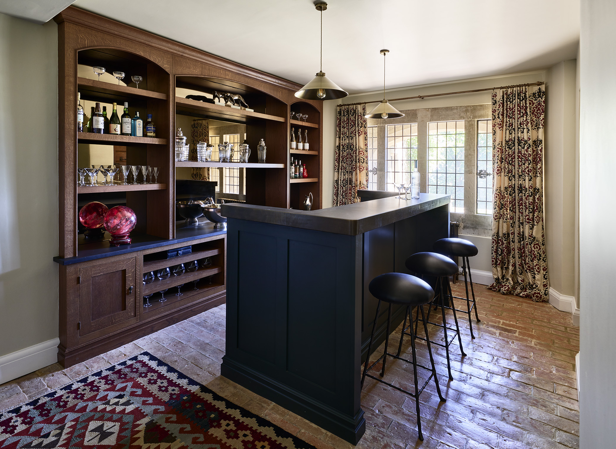 A home bar in dark oak and dark grey lacquer with 3 bar stools and a bar-top