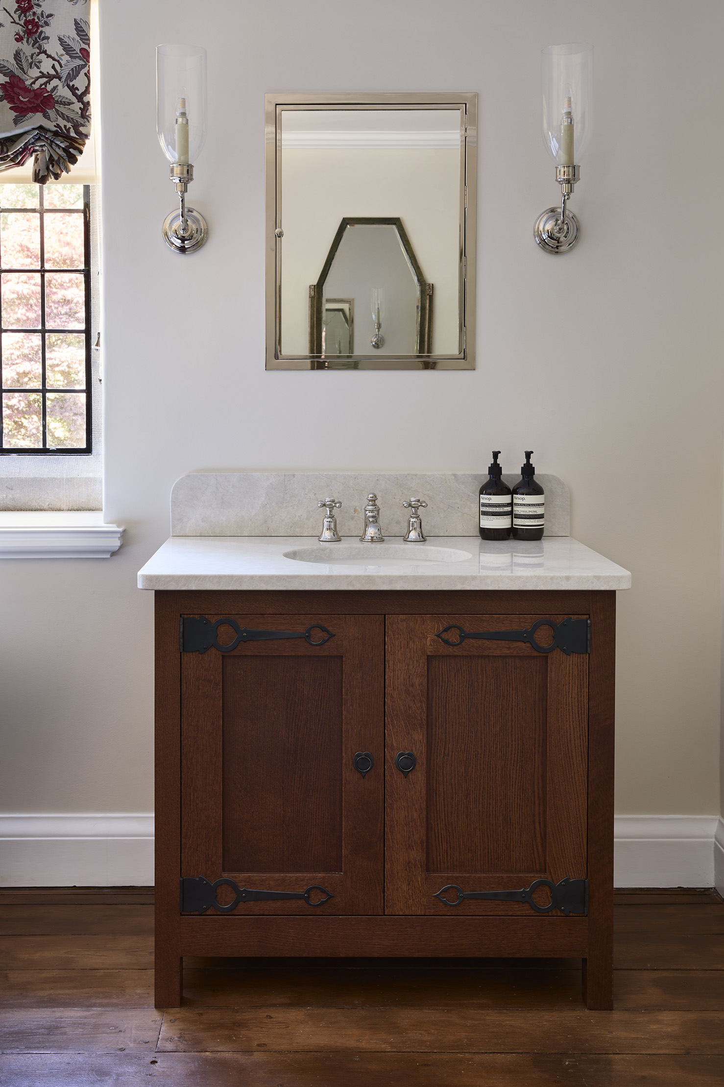 An Arts & Crafts inspired bathroom vanity units in dark stained oak with cream marble top 