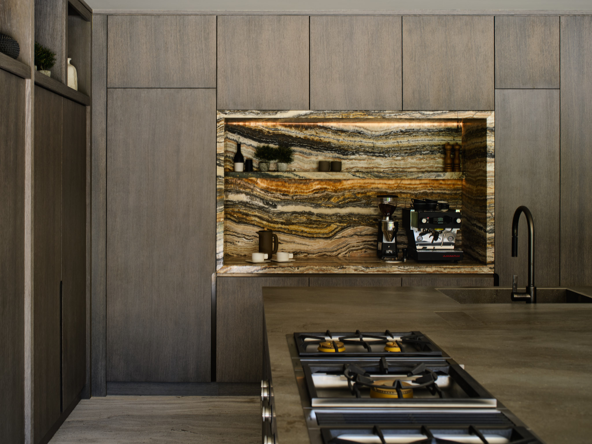 A recess in a tall run of cabinets lined in heavily veined travertine