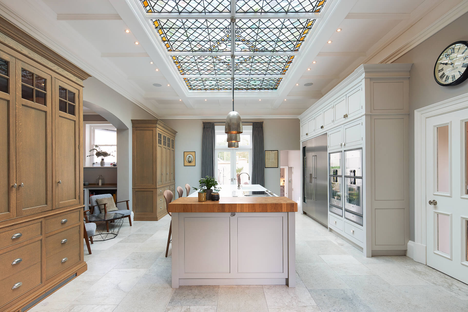 A bespoke kitchen by Hetherington Newman with a white painted island and tall dresser cabinets in oak