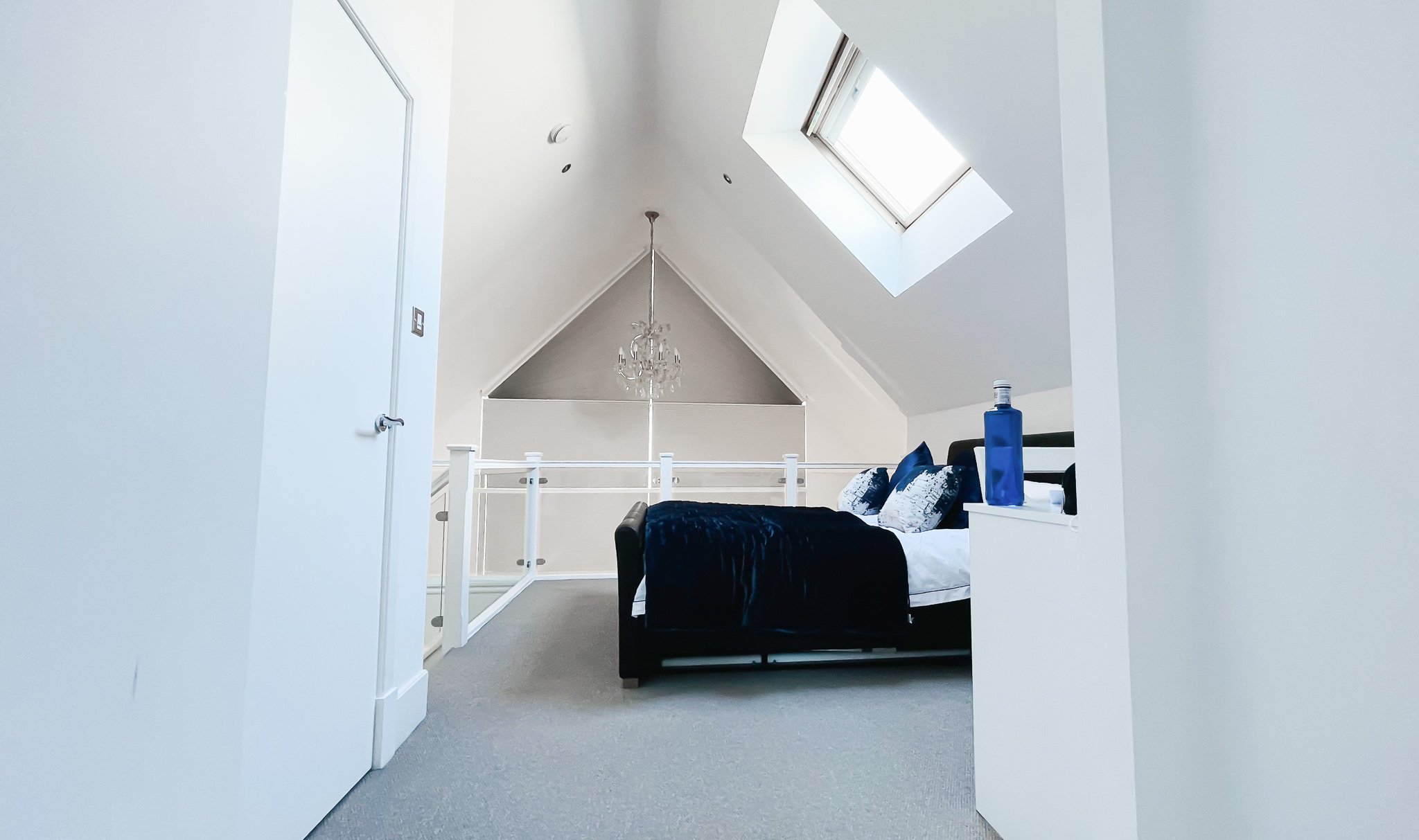 modern bedroom with large apex window fitted with motorised pleated blinds