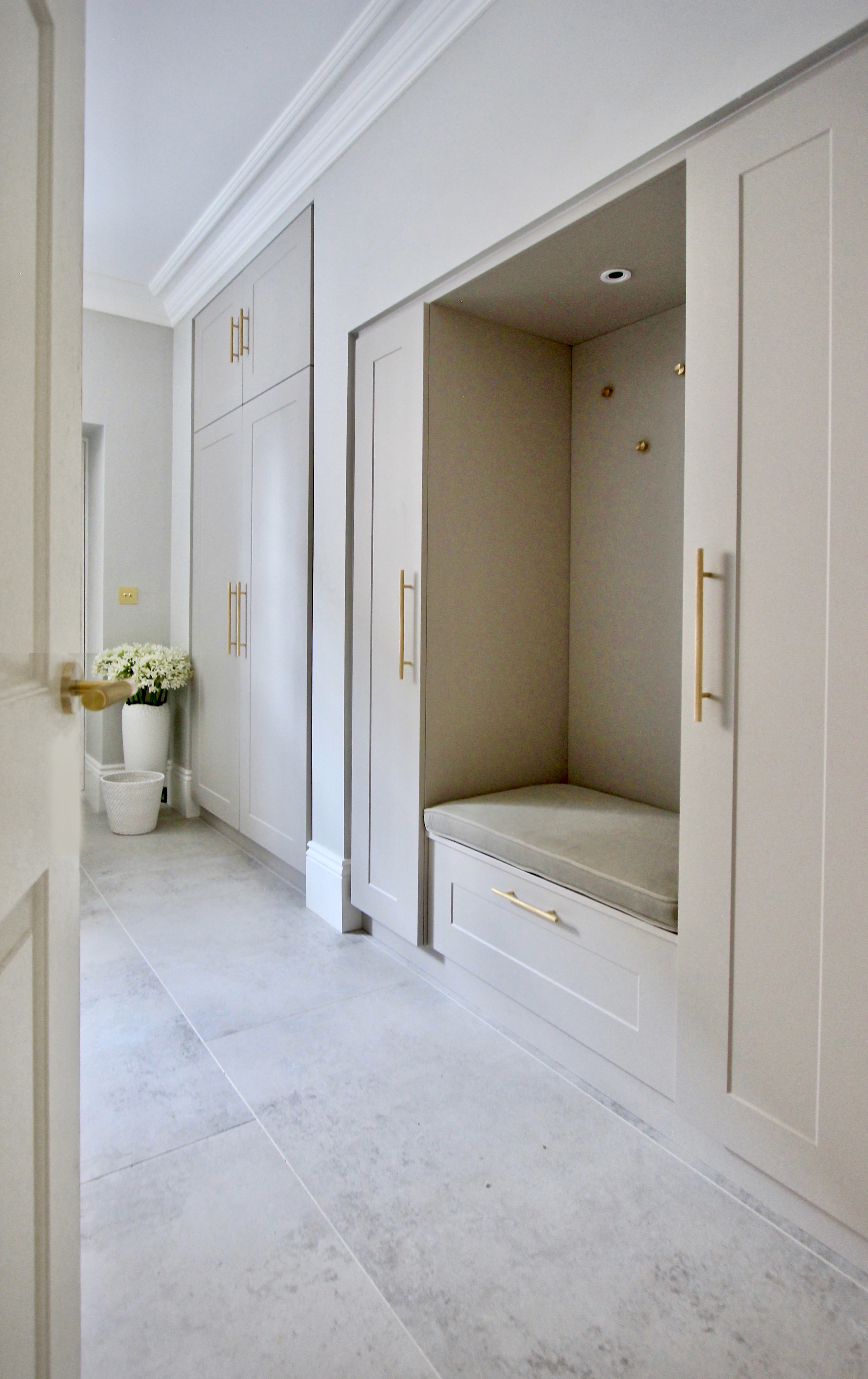and elegant practical light grey boot room with brass handles large porcelain tiles