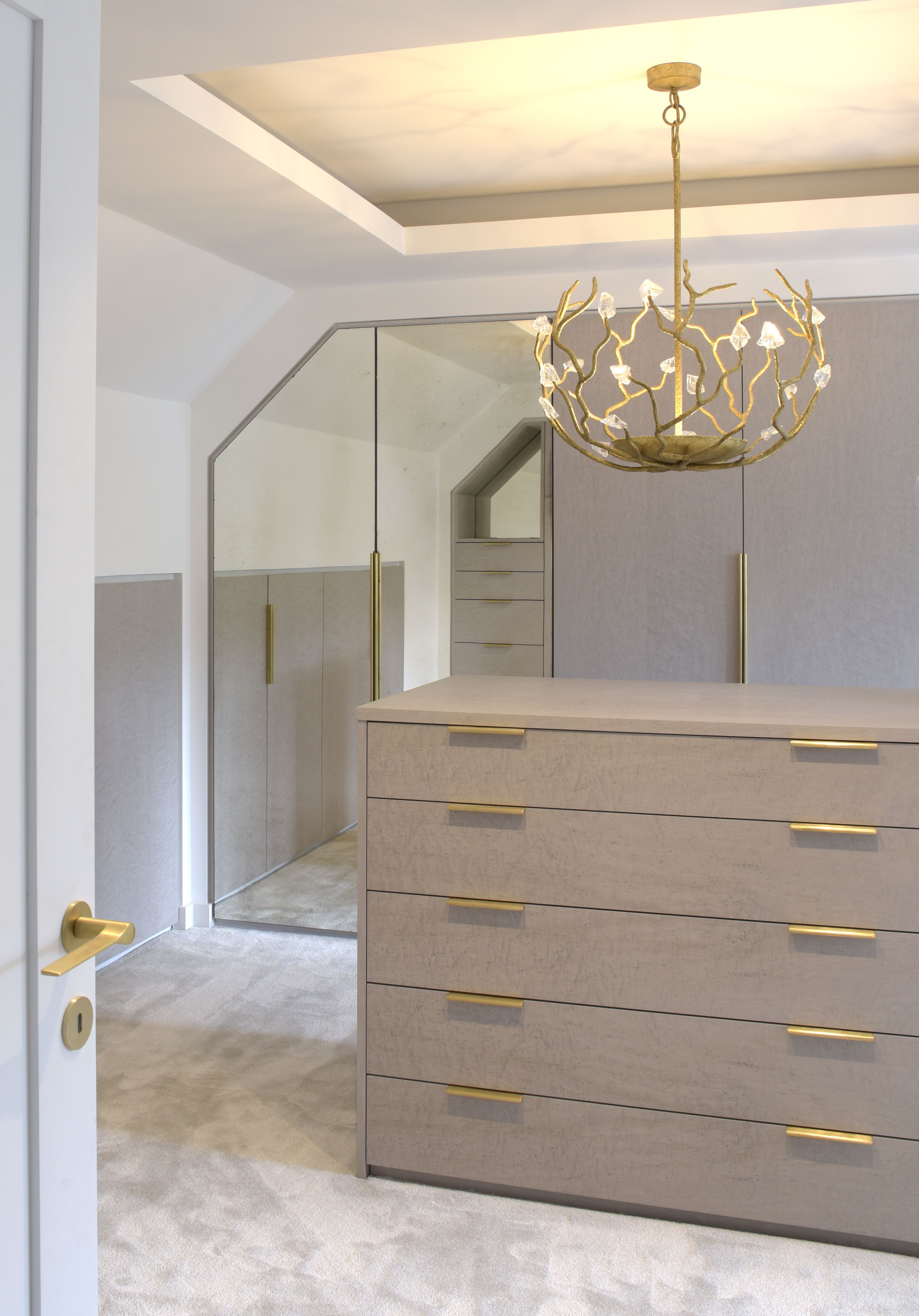 Luxurious dressing room with lit ceiling and central island with gold chandelier