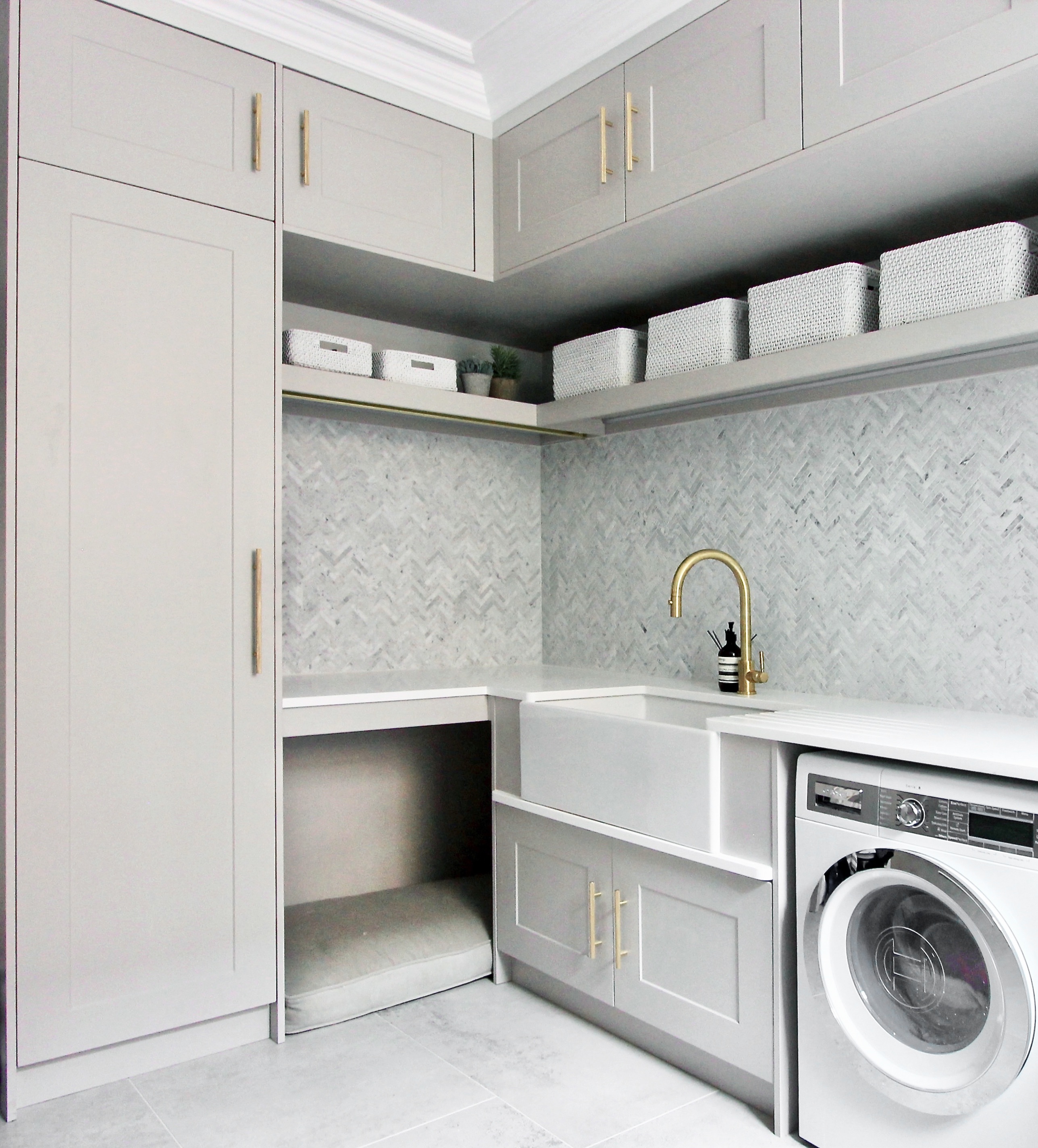 An elegant practical light grey utility room with brass handles