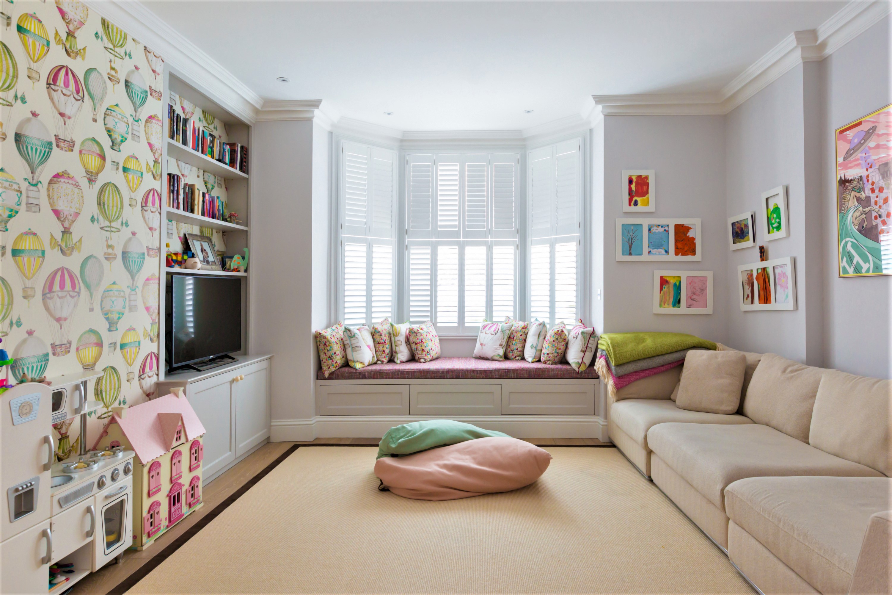 The children's playroom has practical storage, plantation shutters and whimsical wallpaper