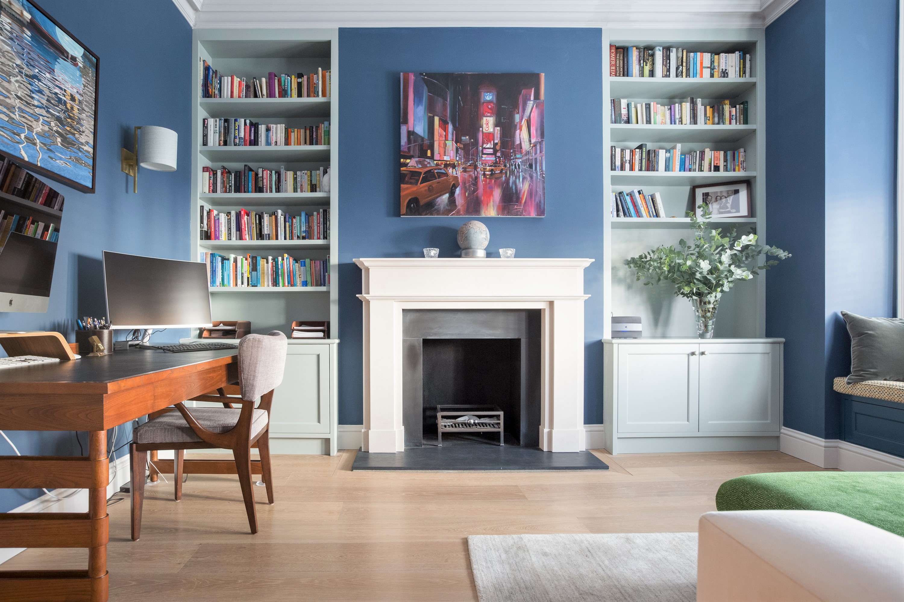 Blues and Greens mix in the home office. Bespoke joinery bookshelves flank the fireplace and set the stage for the Mid-Century Modern artwork and furniture