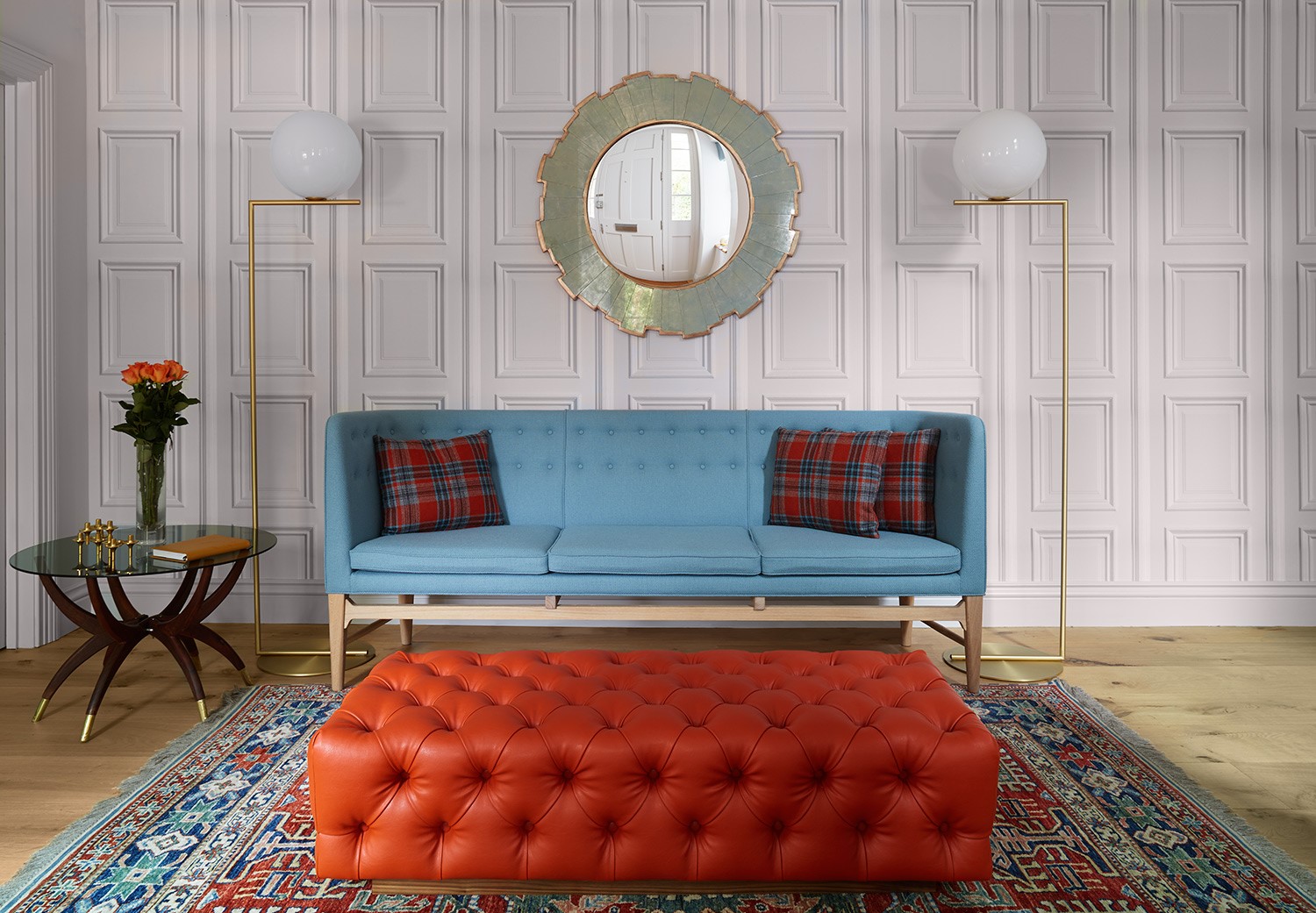 Entrance hall, with blue sofa & feature orange deep buttoned footstool; feature panelling wall paper and design classic lighting.