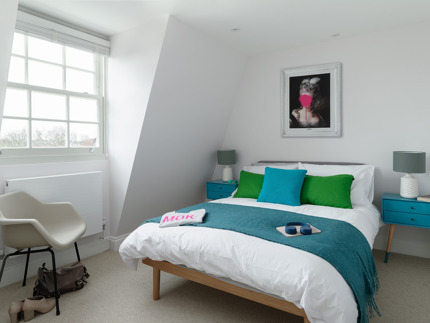 Calm bedroom featuring design classic furniture against a light bright base palette with accent colour pops and bold art work to inject some humour