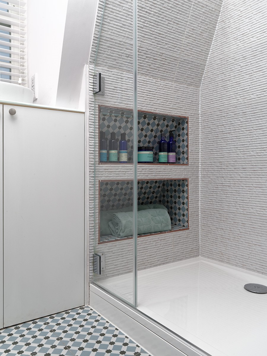 Spacious shower using the eves for storage; shower under eaves; walk in shower; patterned floor tiles; clever bathroom storage
