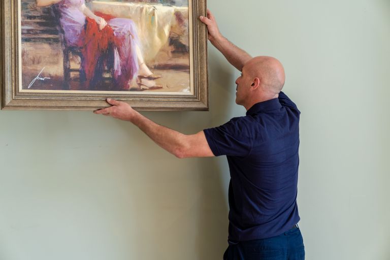 A Clockwork Removals team member carefully hanging up a painting.