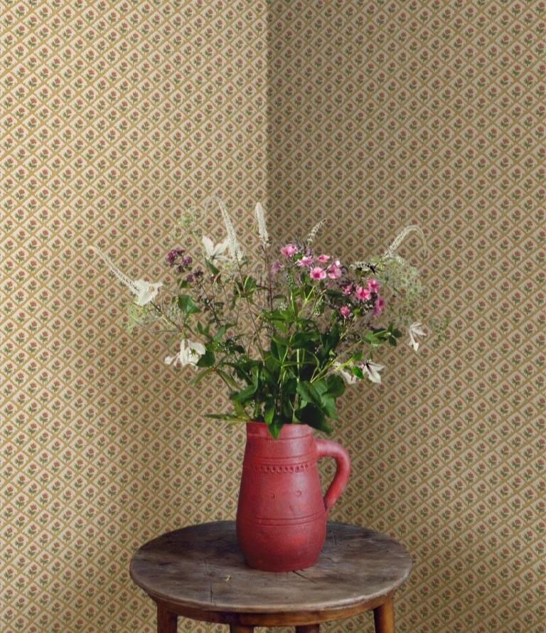 Vase of flowers on a table with diamond patterned wallpaper behind