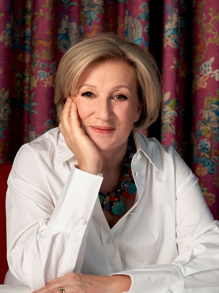 Ann Grafton smiling into the camera with a red floral background