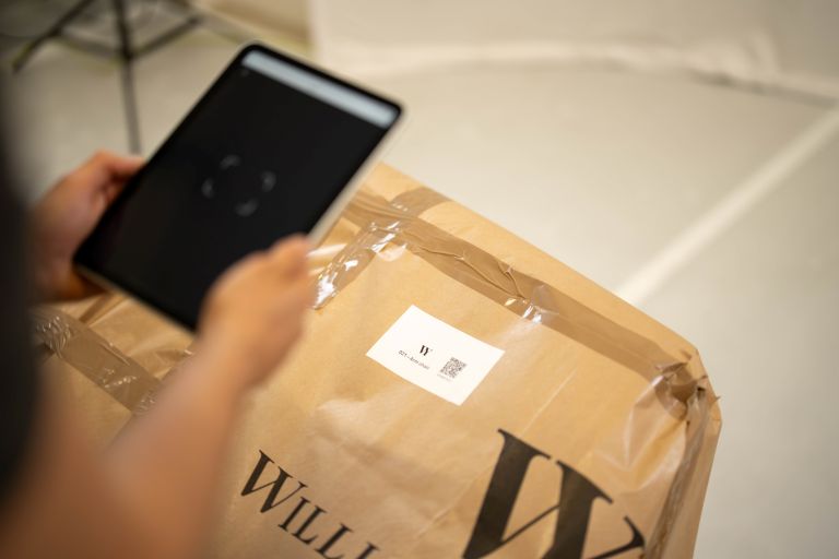 A tablet scanning a QR code on a parcel.