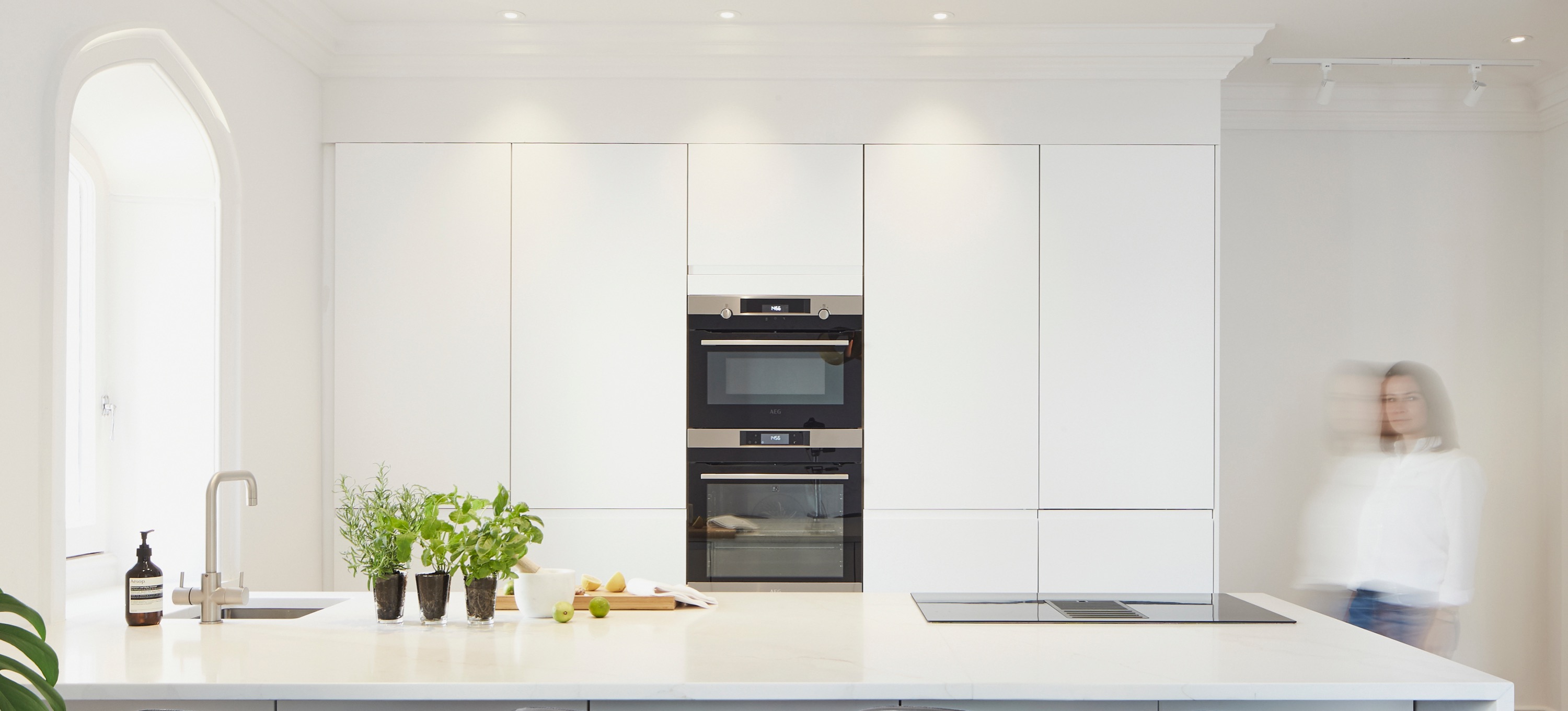Contemporary white handles kitchen with large island waterfall marble worktop