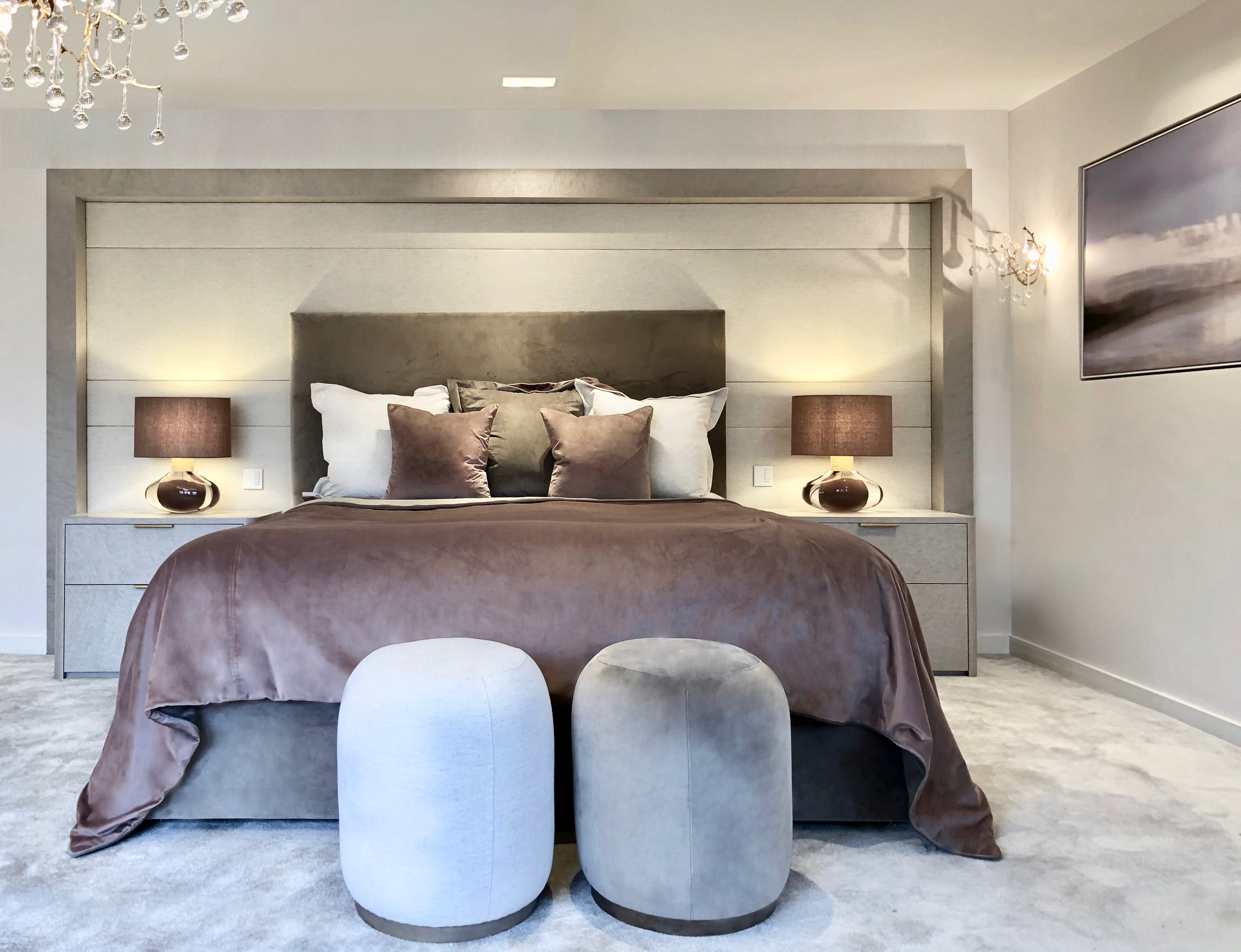 Luxurious master bedroom with oversized velvet  headboard velvet accessories glass table lamps glamorous lighting