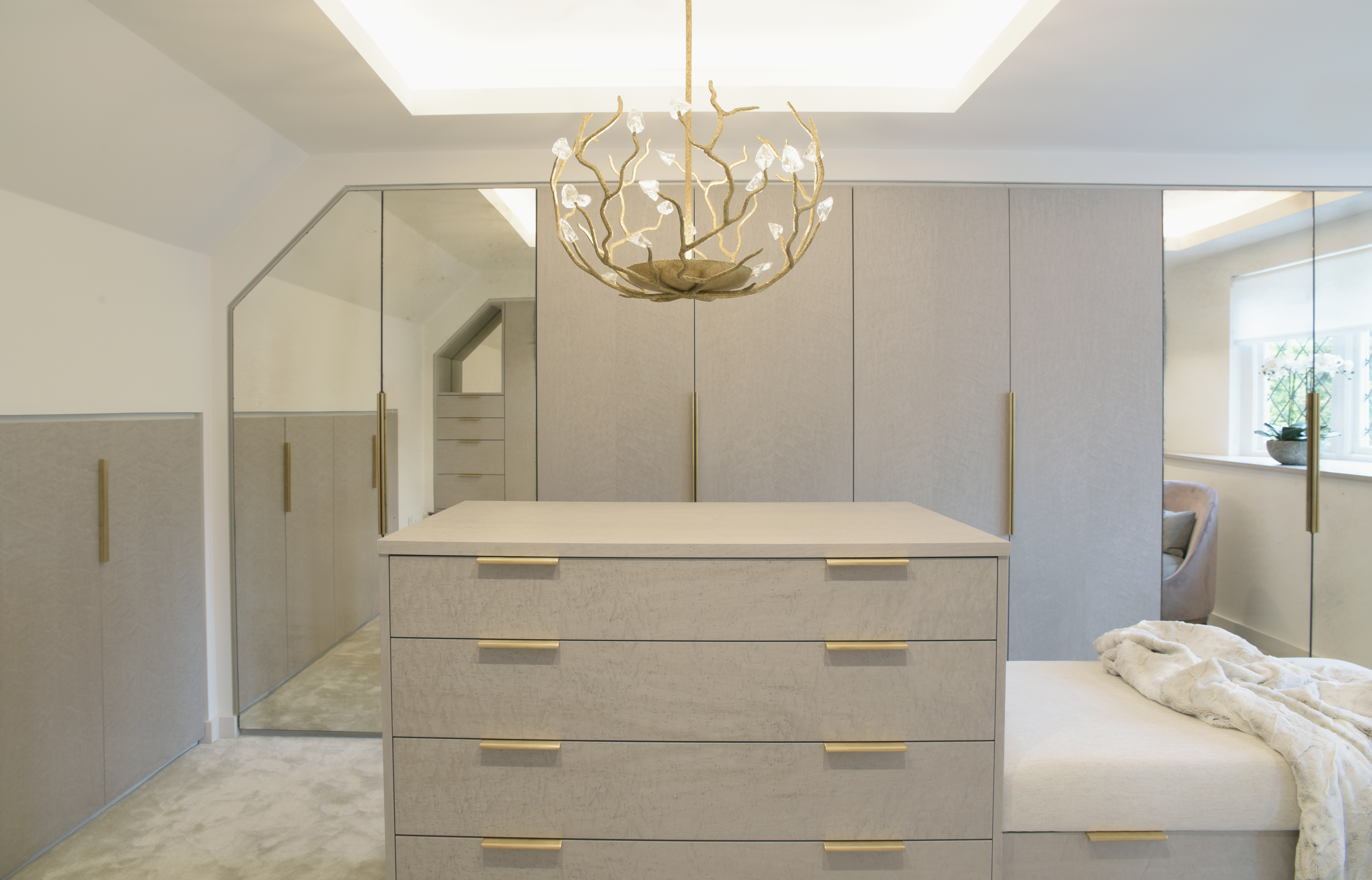 Elegant large dressing room with lit ceiling and central island with gold chandelier