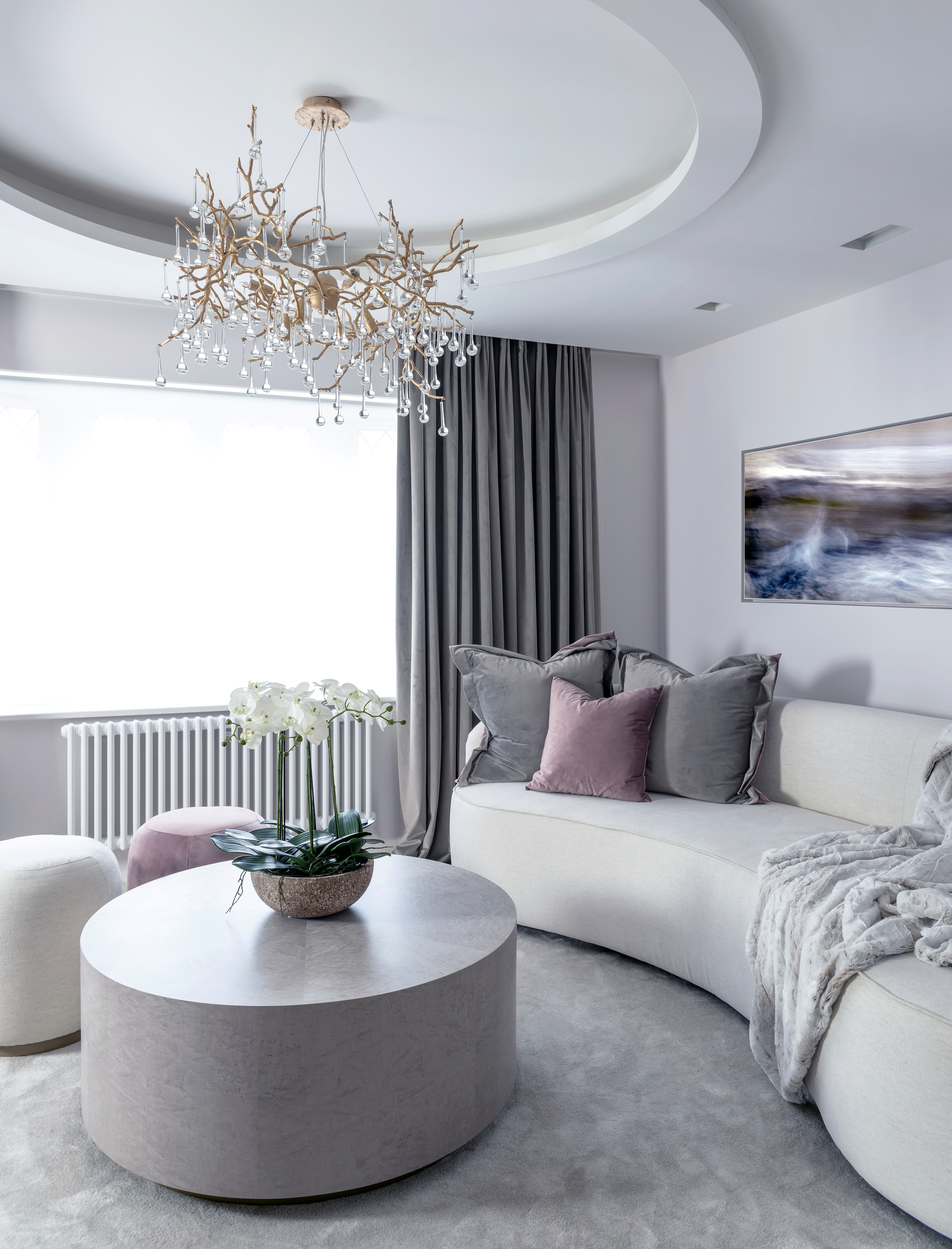 Contemporary and elegant bedroom seating with curved sofa, gold chandelier, velvet accessories