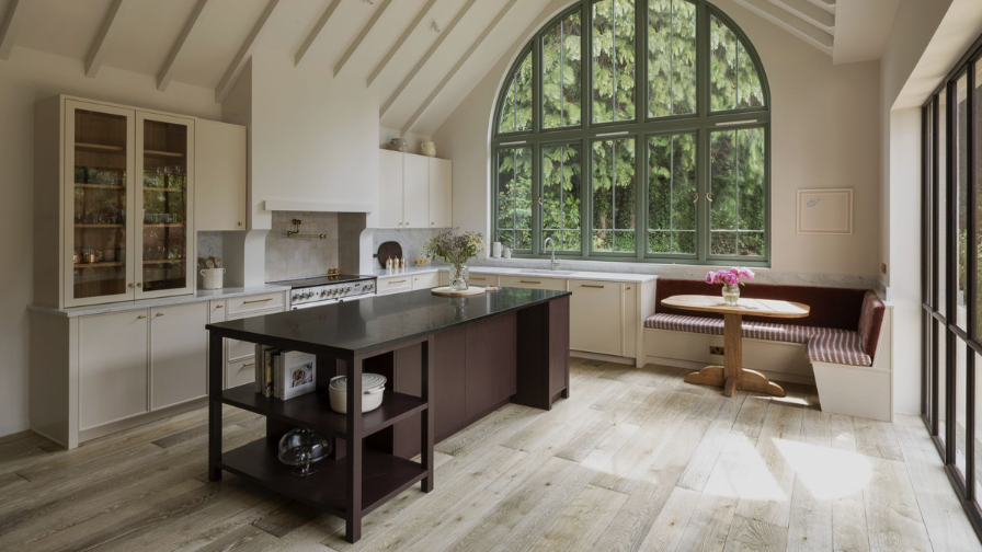 Kitchen with large arched window, a brown island and textured oak floor.