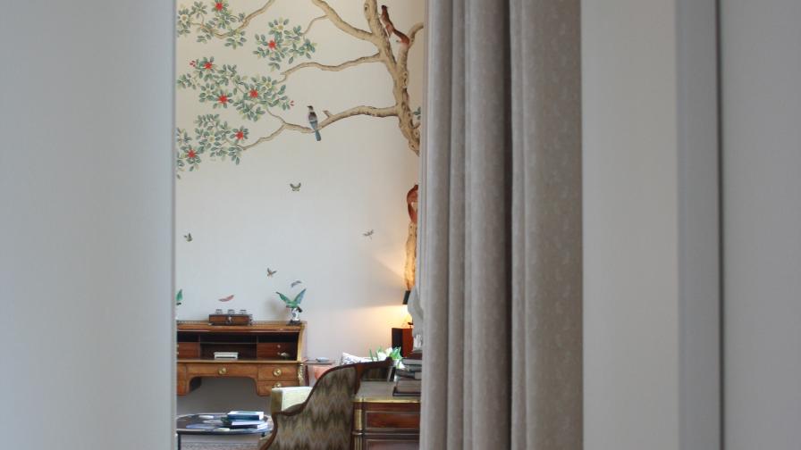 Long Serge neutral curtains frame the entrance to the formal living room, featuring a bespoke hand painted and hand embroidered mural