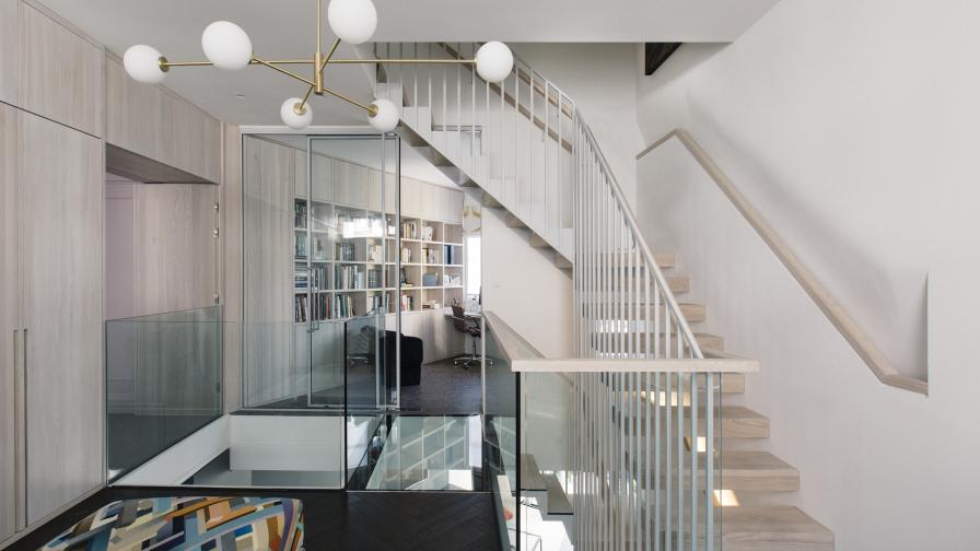 A modern chandelier and glass bridge greet visitors in the entrance hall