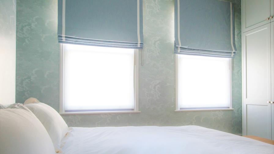 A dreamy and peaceful guest bedroom; cloud patterned wallpaper of heavenly blues ties in with the blue roman blinds