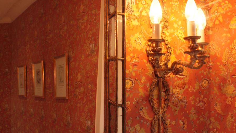 The Cloakroom Chinoiserie wallpaper, antique gilt mirror and wall sconces in detail