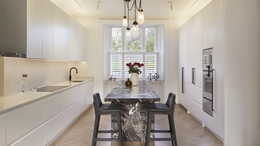 A kitchen with white cabinets & a red & white marble island 