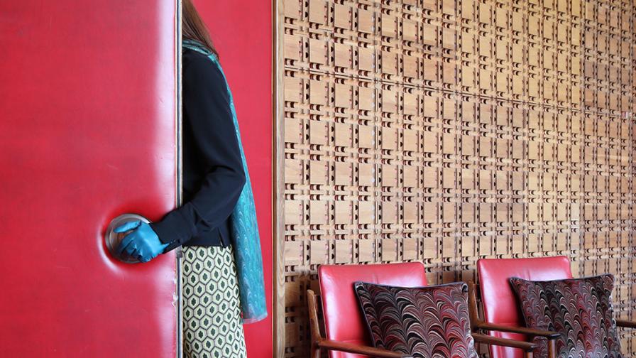 Woman walking through a doorway with 2 chairs beyond with Susi Bellamy cushions