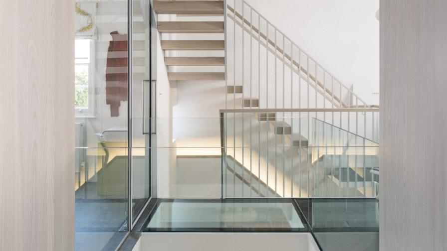 A floating staircase of white oiled ash hovers above the glass bridge and central void, allowing for maximum light