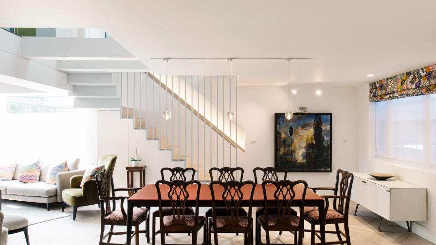 The modern red glass and walnut dining table sits happily with the Chippendale dining chairs under Bocci pendants