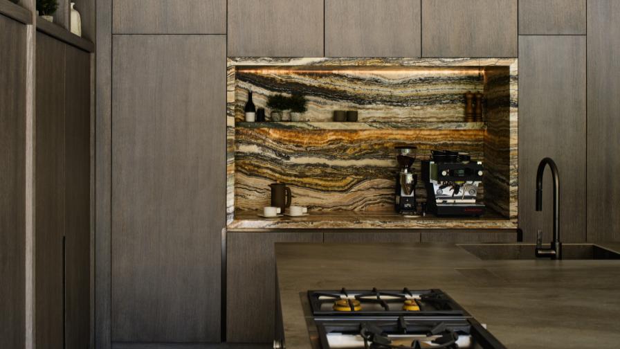 A recess in a tall run of cabinets lined in heavily veined travertine