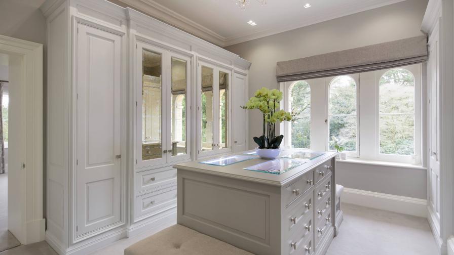 A White painted dressing room by Hetherington Newman with wardrobes and a central storage unit