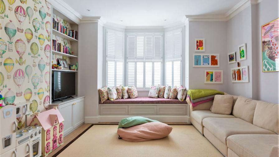 The children's playroom has practical storage, plantation shutters and whimsical wallpaper