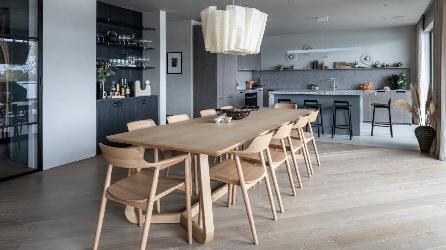 dining room with light oak floor and open plan kitchen in the background.