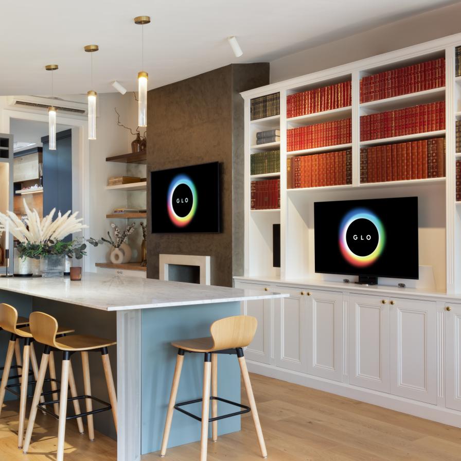 A modern, stylish kitchen and living area featuring a large marble island with seating for three