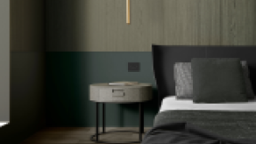 Side of a large bed with dark bedding and panelled walls behind