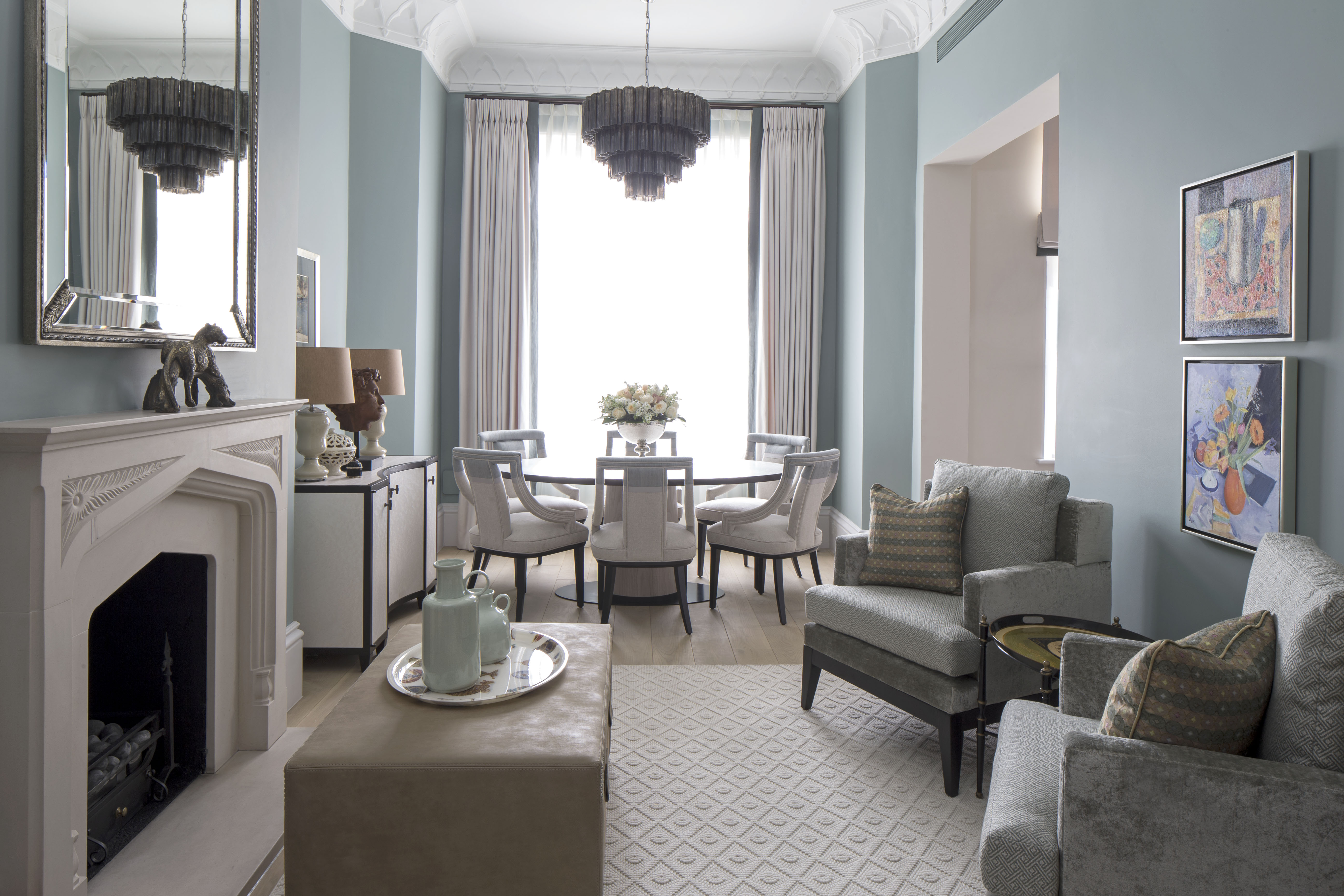 elegant living room with pale blue walls, round dining table and glass chandelier